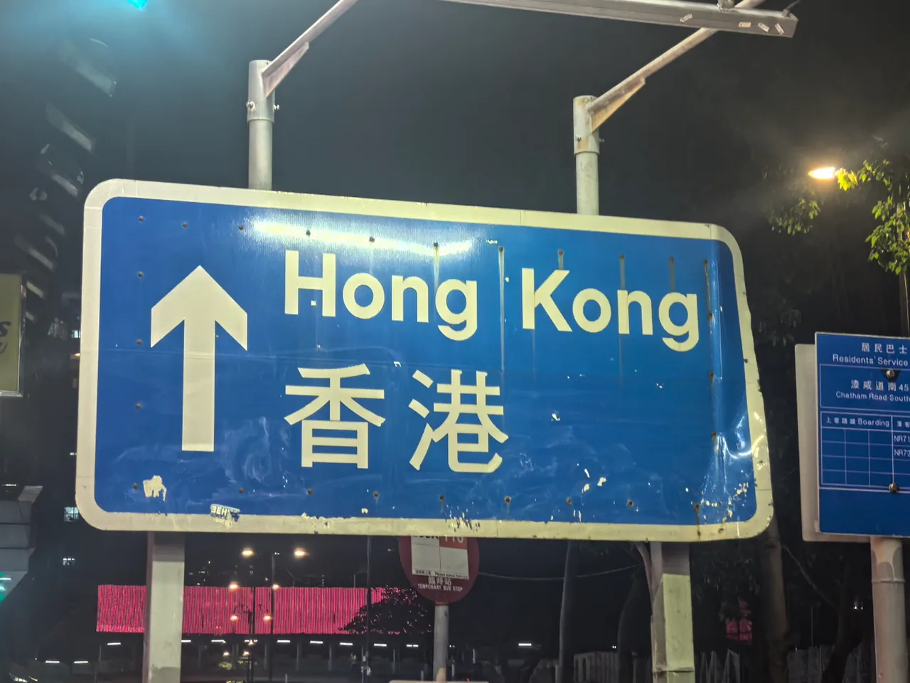 夜色中的蓝色“Hong Kong / 香港”道路指示牌